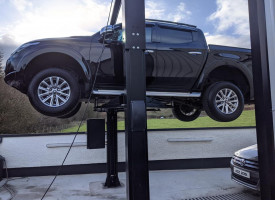 A car lift lifting a four wheel drive.